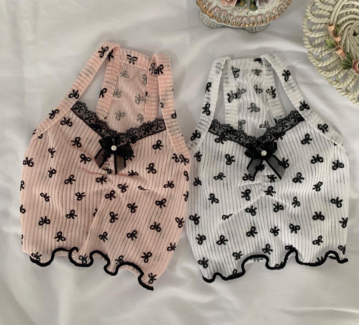 Two NKpup bow crop top dog shirts, one in light pink and one in white, featuring black bow and lace trim.