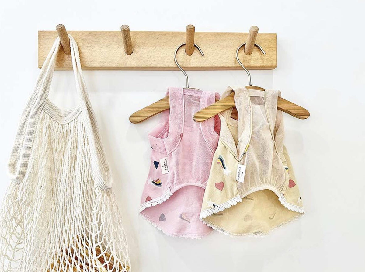 Two NKpup rainbow print dog dresses in pink and cream with lace trim.
