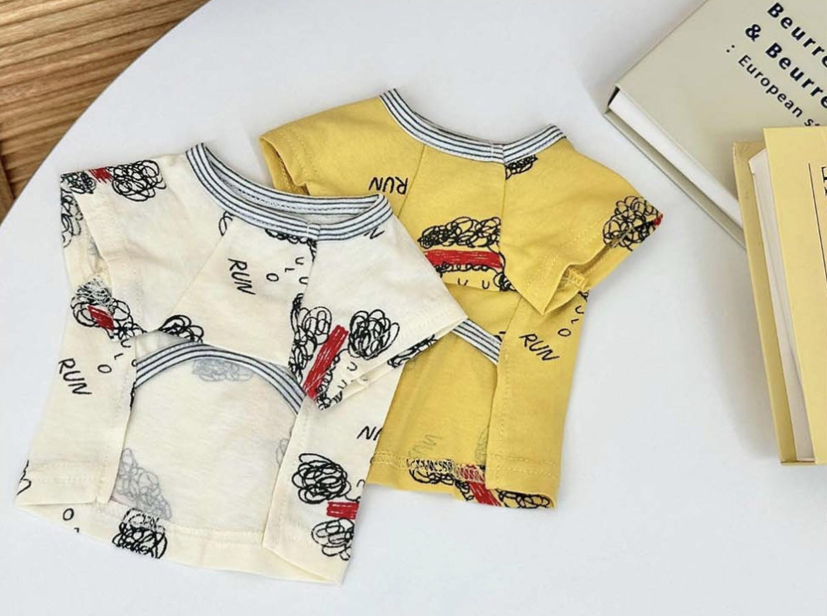 Two NKpup Run Sketch Tee dog shirts, one white with black and red sketches and one yellow with black sketches.