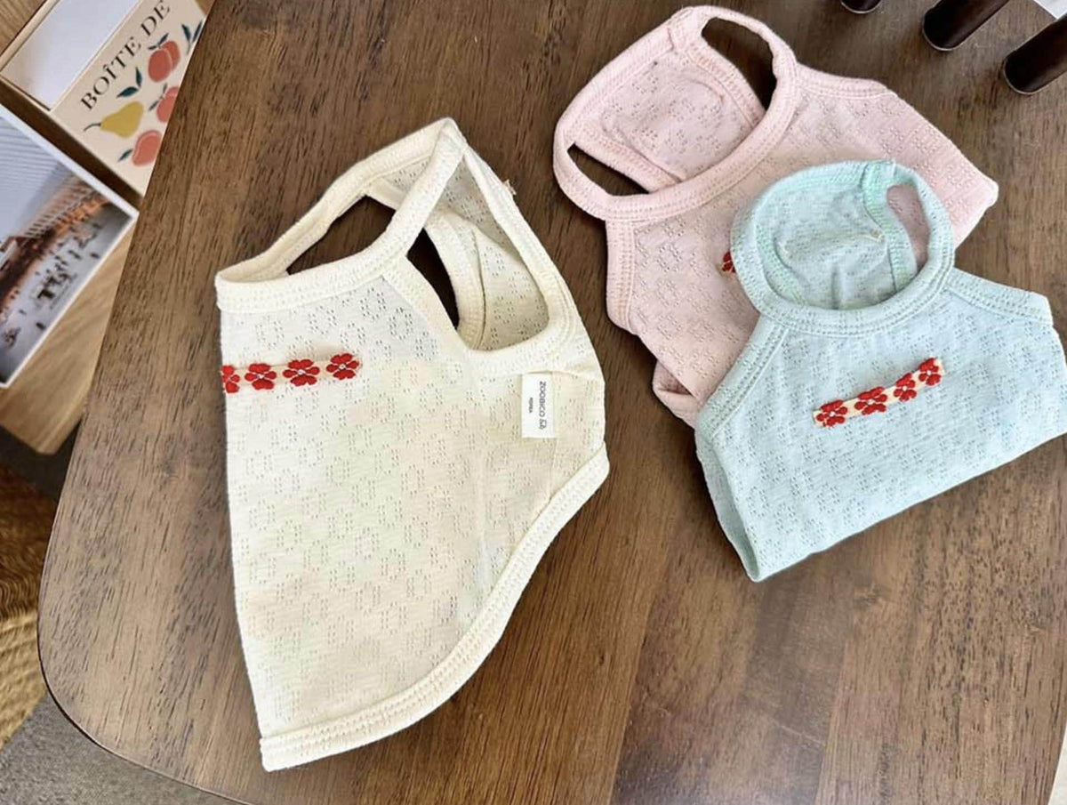 Three eyelet floral tank tops for dogs in cream, pink, and light blue.