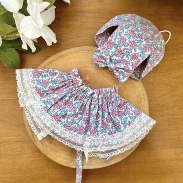 Floral pattern pet cape and matching bonnet with white lace trim.