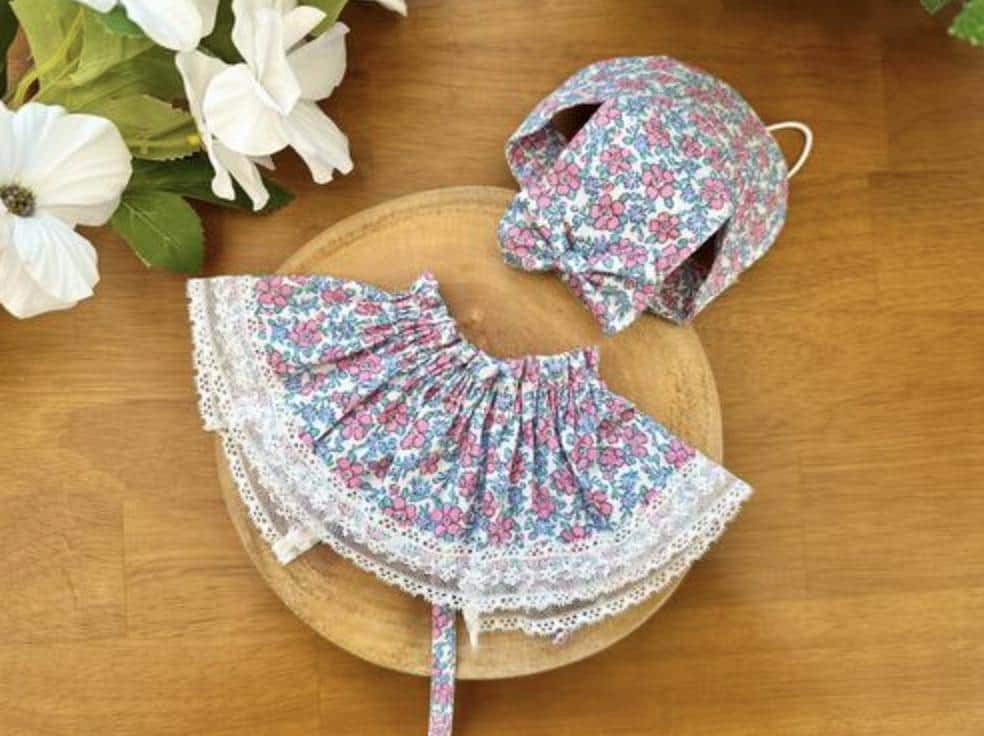 Floral pattern pet cape and matching bonnet with white lace trim.