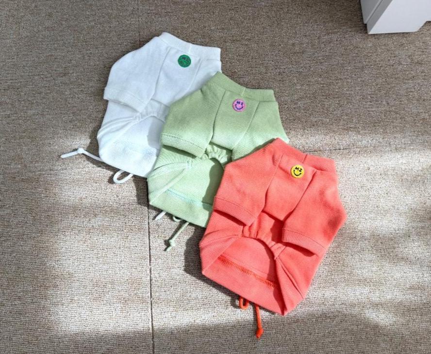 Three NKpup minimal drawstring sweatshirts for dogs in white, light green, and coral pink.