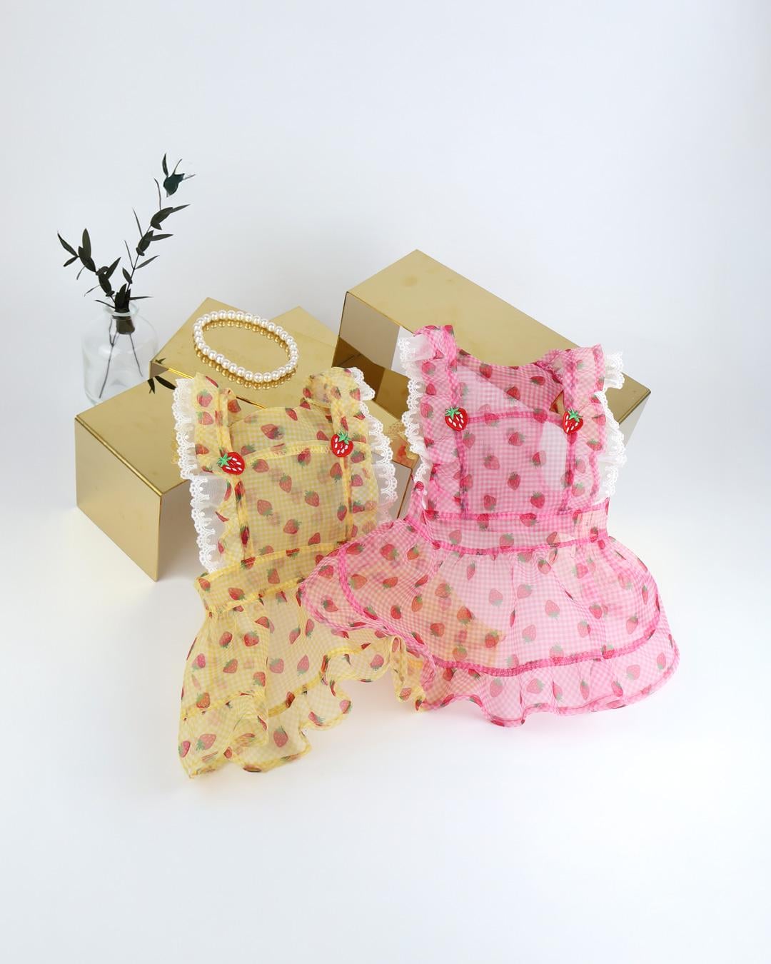 NKpup Strawberry Picnic dog dresses in pink and yellow with strawberry patterns and white ruffle trim.