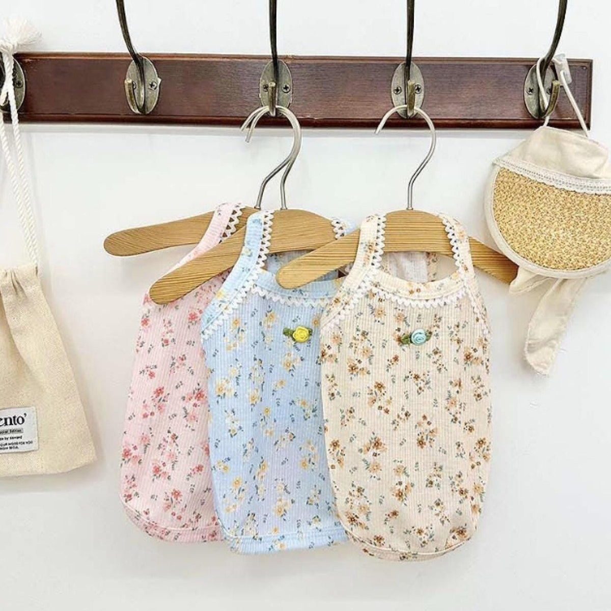 Three ribbed pet tops in pink, blue, and cream floral patterns hanging on hangers.