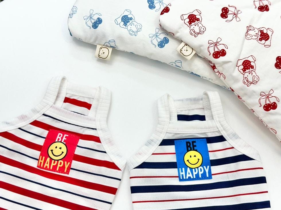 Two NKpup Be Happy cooling mesh sleeveless dog shirts with smiley face patches in red and blue stripes.