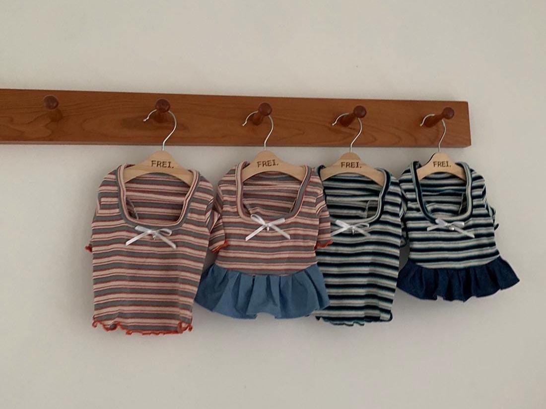 Four sailor stripe pet outfits in pink and blue with bow details hanging on a wooden rack.