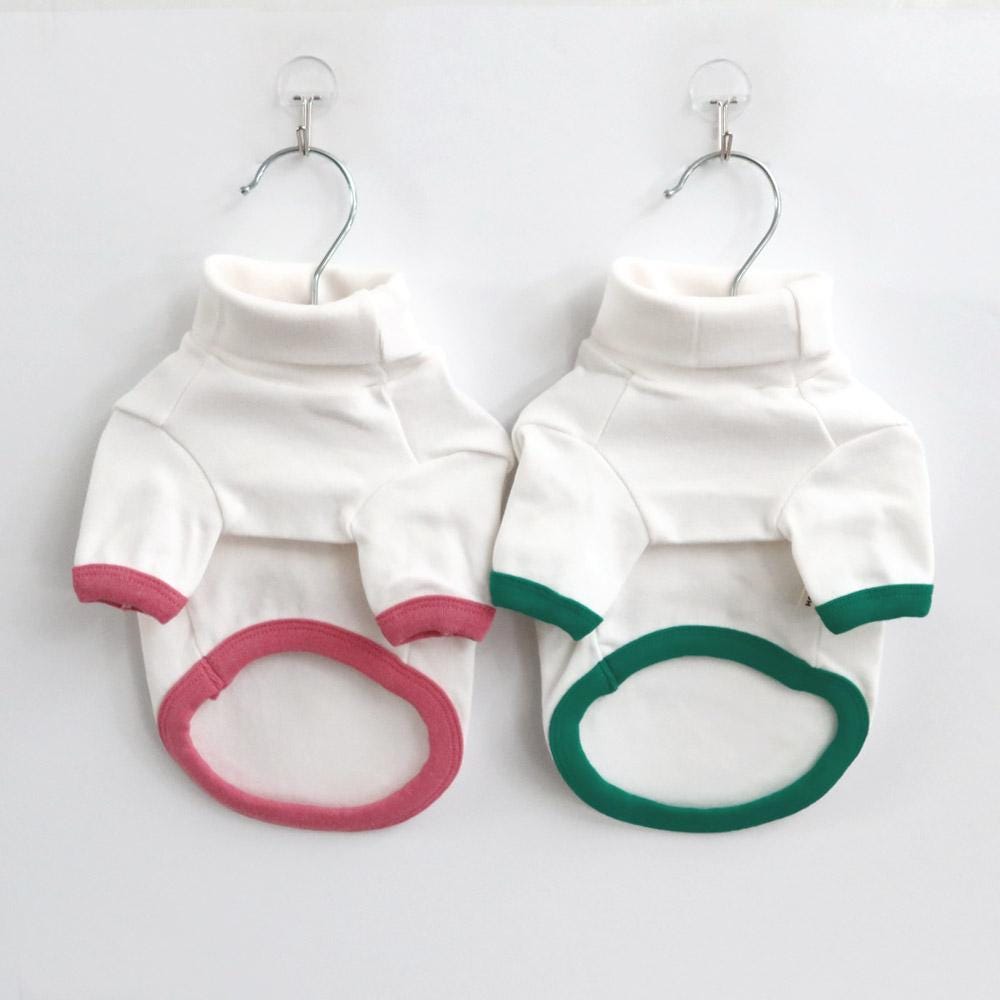 Two NKpup soft turtleneck dog shirts in white with pink and green trim.