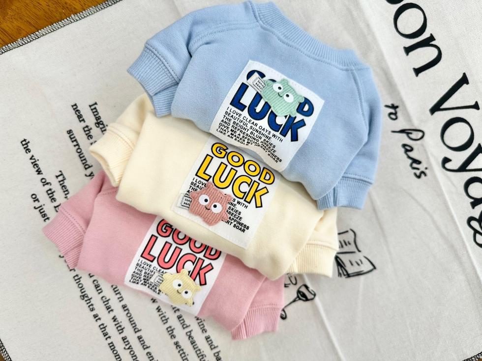Set of three NKpup Good Luck sweatshirts for pets in blue, cream, and pink colors.