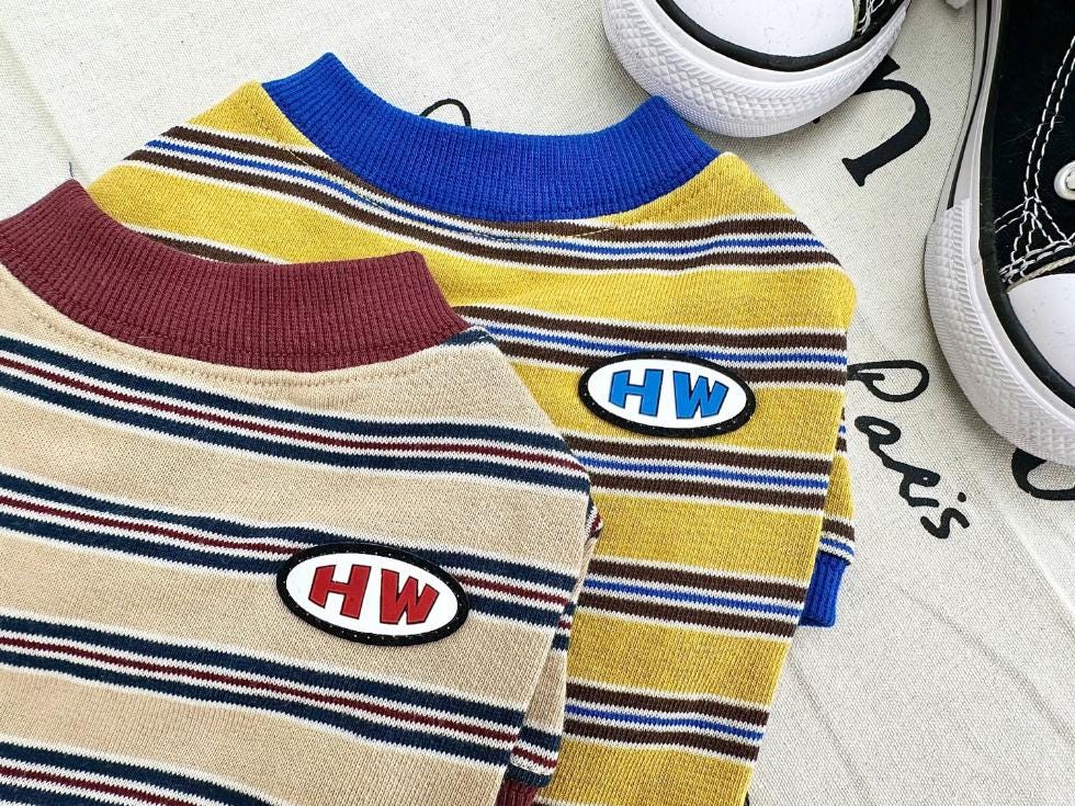 Two HW Stripe Dog Shirts, one yellow with blue trim and one beige with maroon trim.