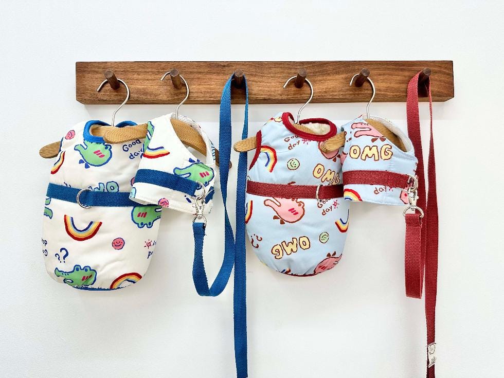 NKpup OMG D-Ring padded dog vests in white and light blue with colorful cartoon patterns.