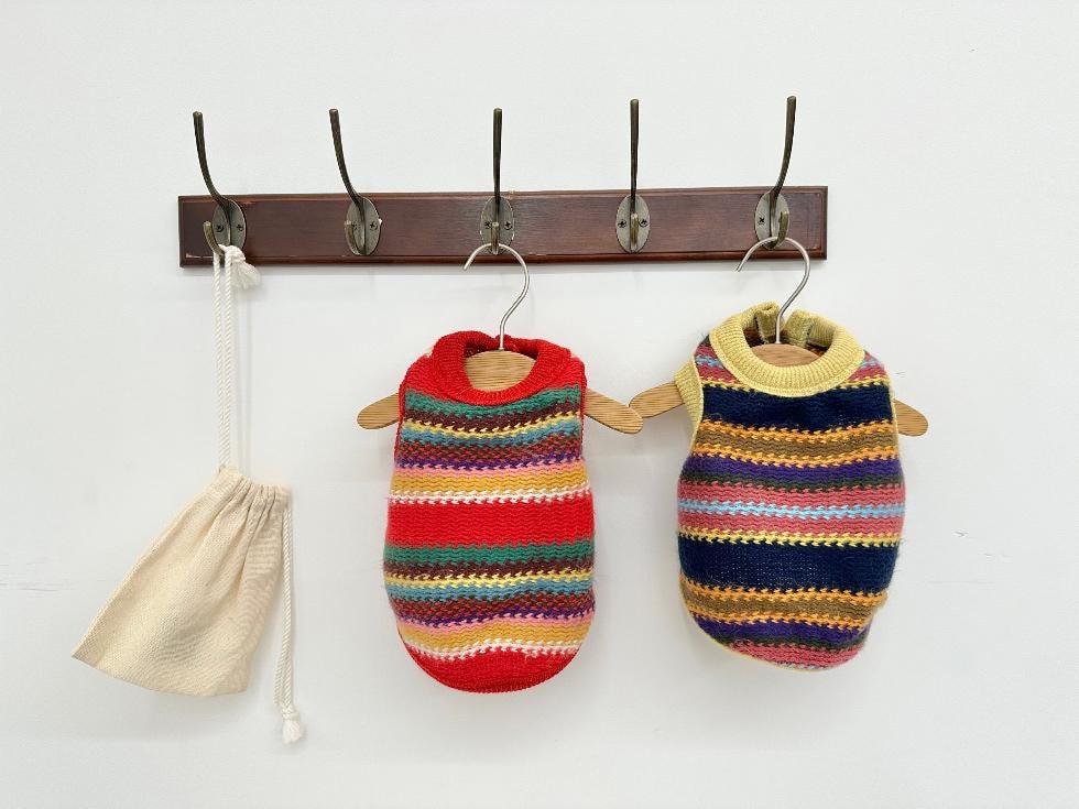 Two NKpup Bene Zigzag Knit Dog Vests in red and yellow multi-colored striped patterns.