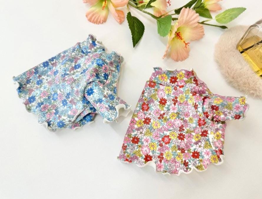 Two NKpup Floral Garden Crop Tees for dogs in blue and pink floral patterns with scalloped edges.