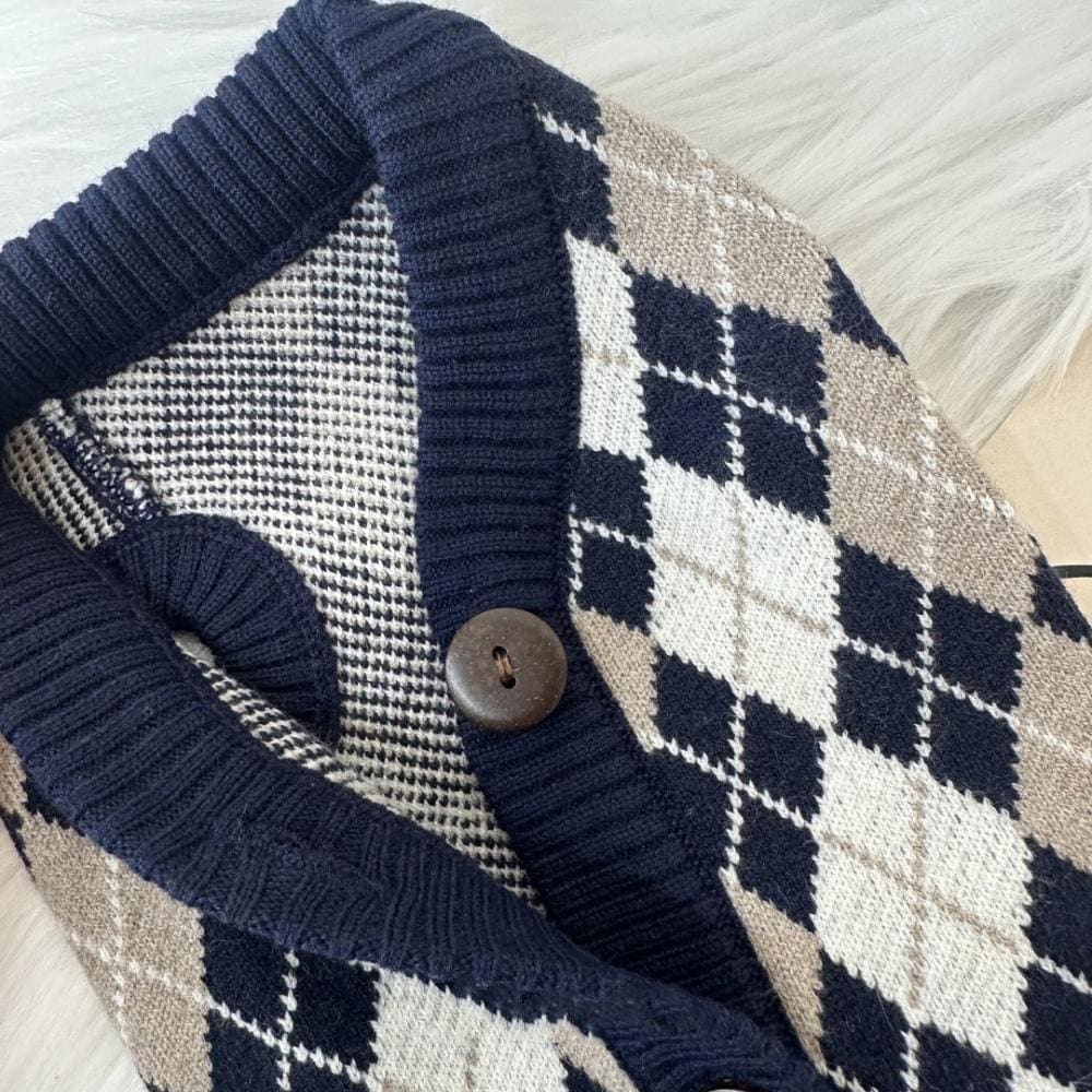 Close-up of NKpup Argyle knit dog cardigan in navy, beige, and white with a button detail.