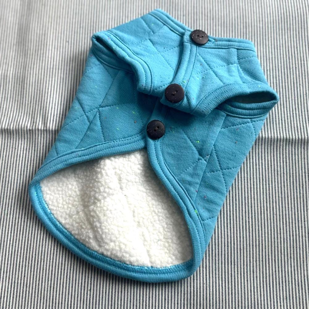Light blue quilted NKpup dog vest with dark brown buttons and white fleece lining