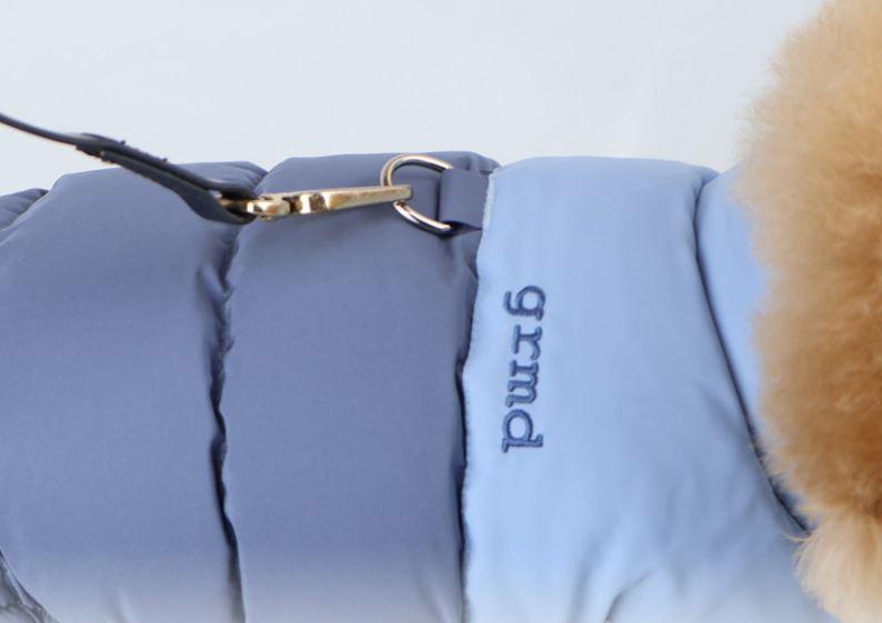 Close-up of a light blue reversible padded dog vest featuring a gold D-ring and faux fur trim.