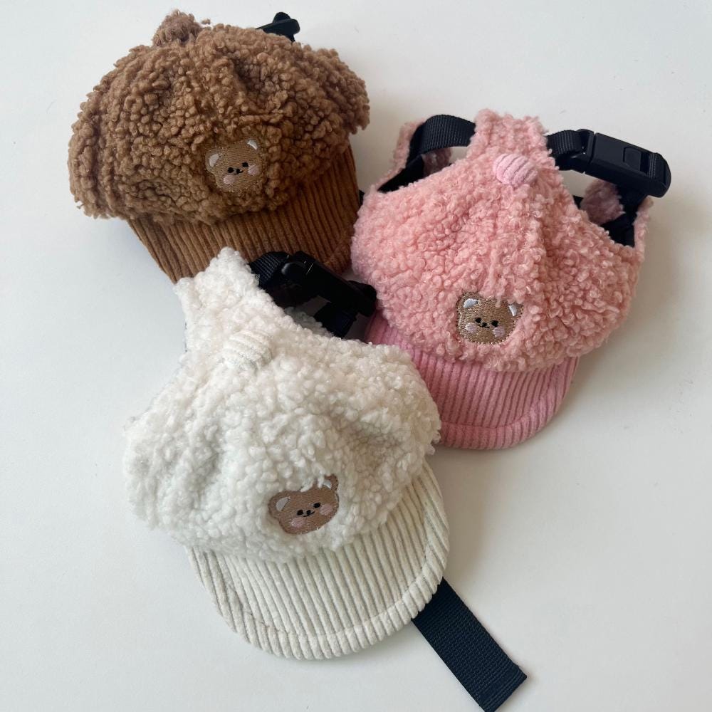 Three teddy fleece caps in brown, pink, and white with cute bear embroidery.