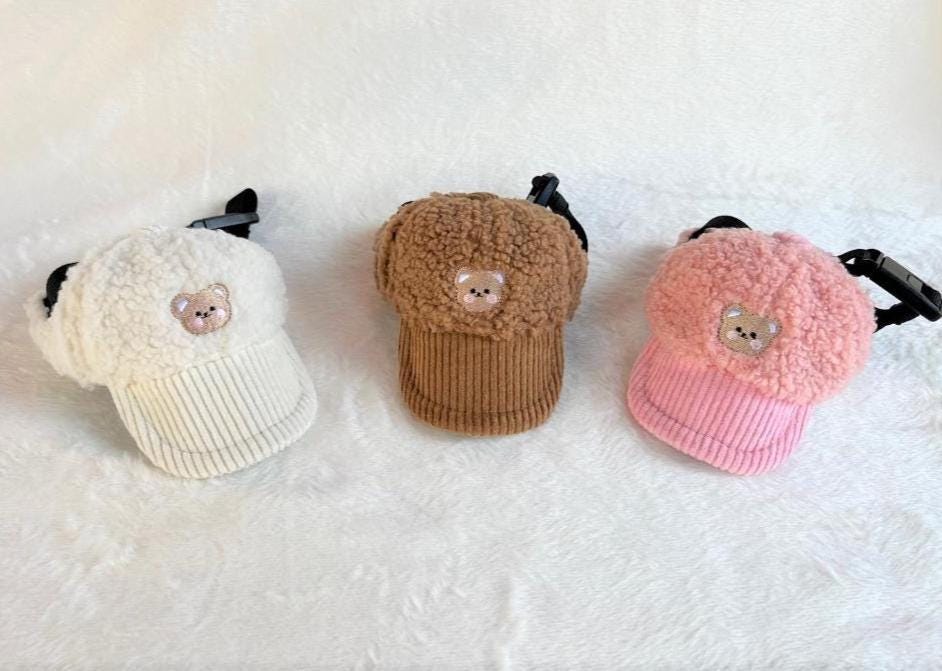 Three teddy fleece pet caps in white, brown, and pink featuring a small bear face detail.