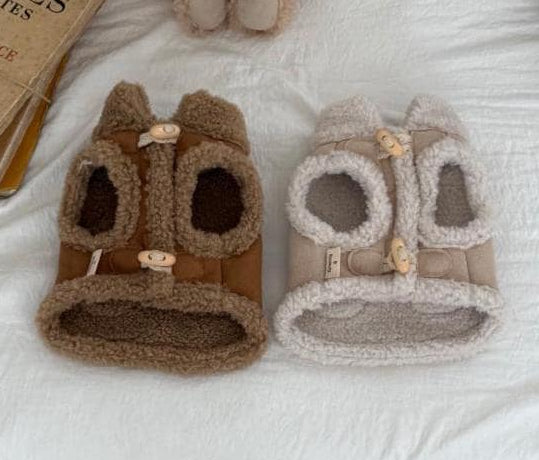 Two cozy shearling vests for dogs in tan and cream colors with button closures.