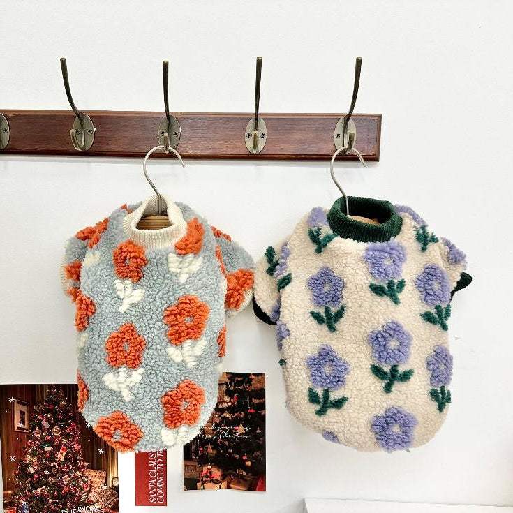 Two fluffy fleece dog sweaters with floral patterns in light blue with orange flowers and cream with purple flowers.