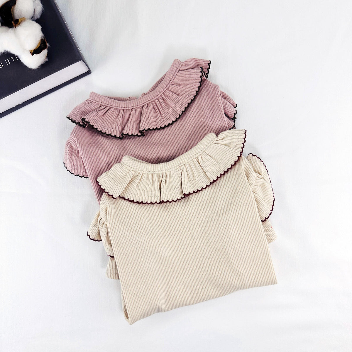 Two ribbed dog shirts with ruffle collars, one in dusty pink and one in cream.