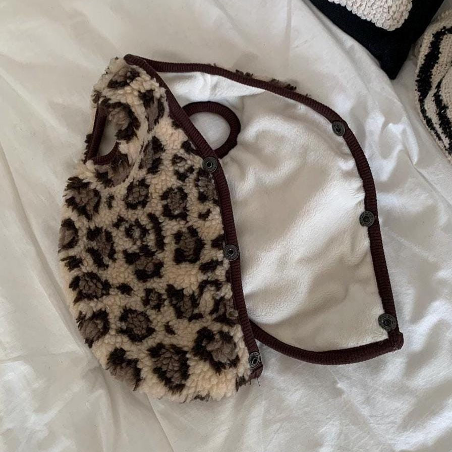 Leopard print fleece vest for dogs with brown trim and snap button closures.