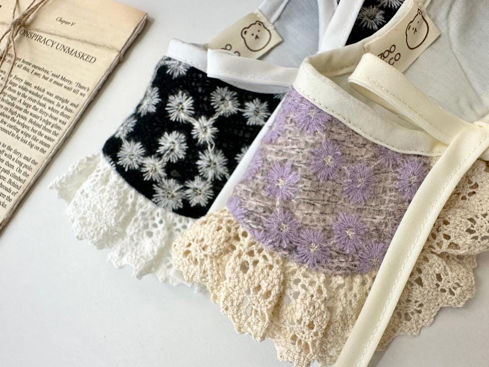 Floral lace dog cape in white and lavender with ruffled lace trim.