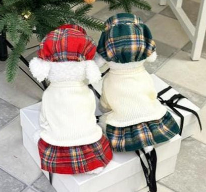 Two dogs wearing holiday plaid knit dog dress and hat sets in red and green patterns.