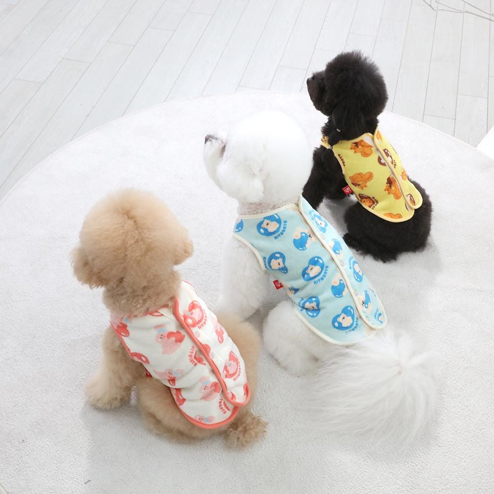 Three dogs wearing colorful patterned microfiber winter dog vests in pink, blue, and yellow.