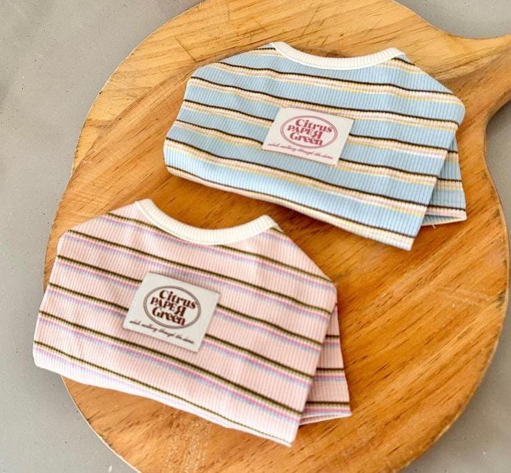 Two ribbed dog shirts with colorful horizontal stripes, one in blue and one in pink.