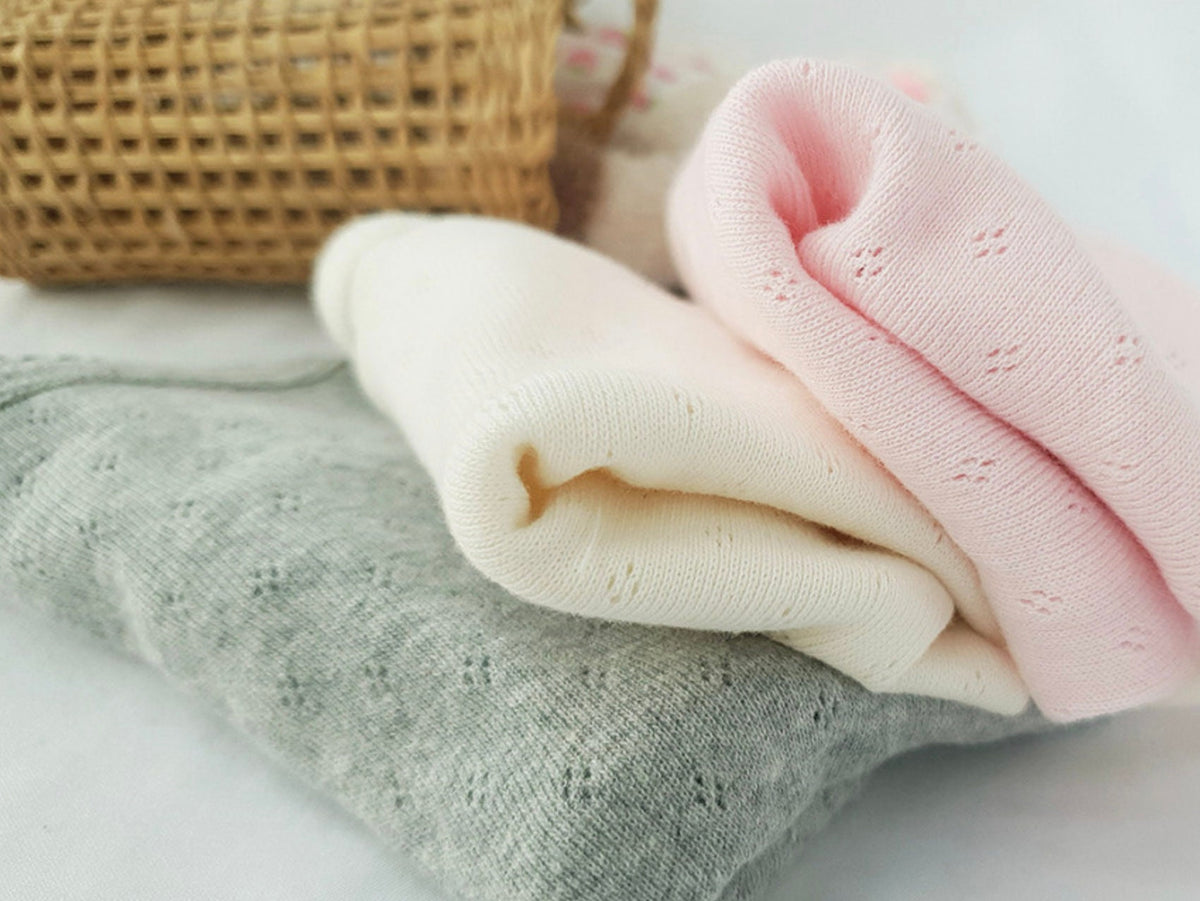 Folded NKpup basic ribbed dog shirts in pink, cream, and grey