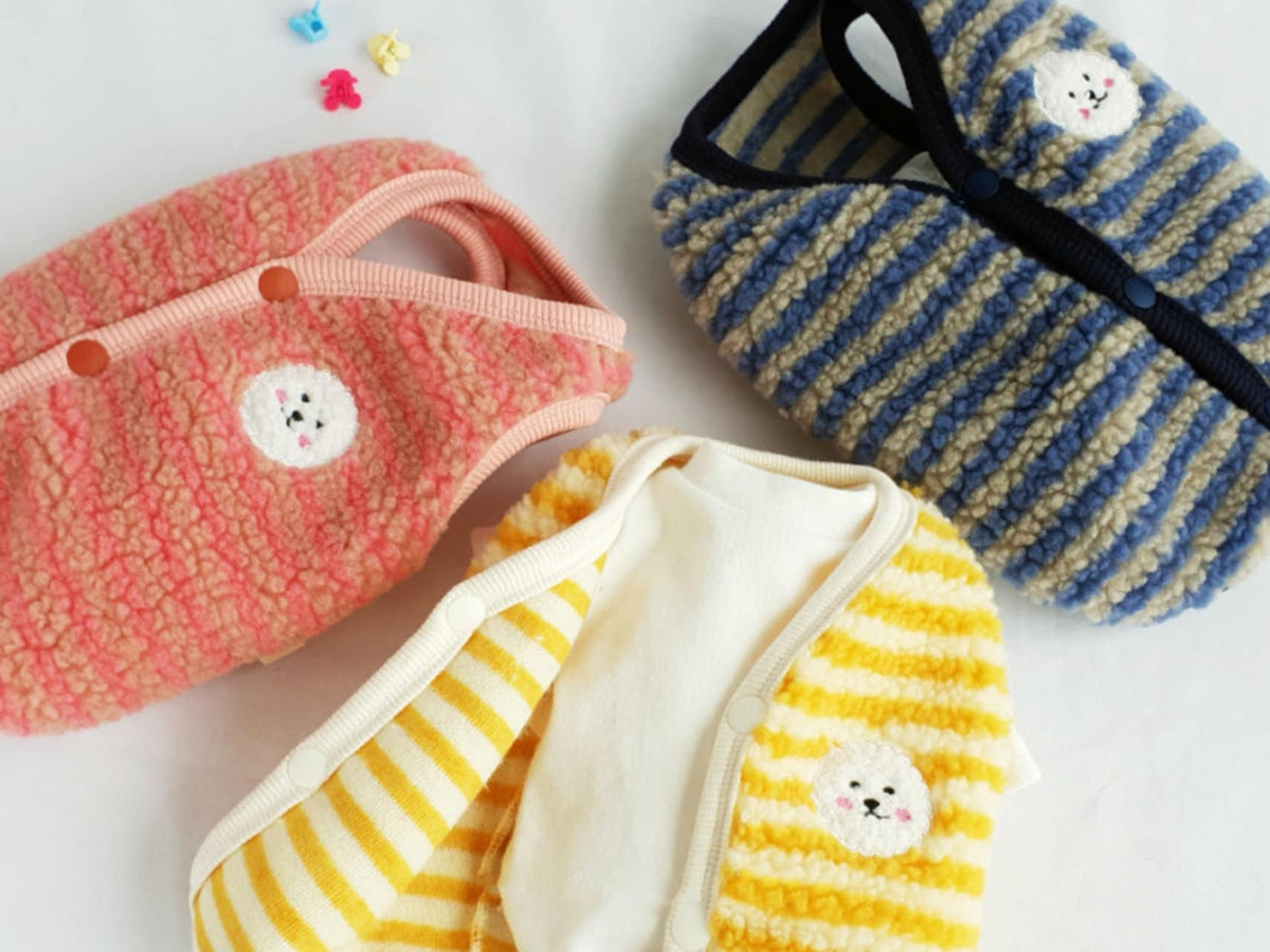 Three striped fleece dog vests in pink, blue, and yellow with cute puppy patches.