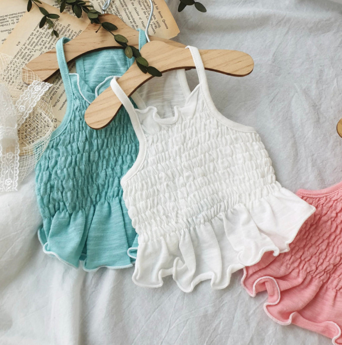 Solid smocked dog crop tops in teal, white, and pink with ruffled hems.
