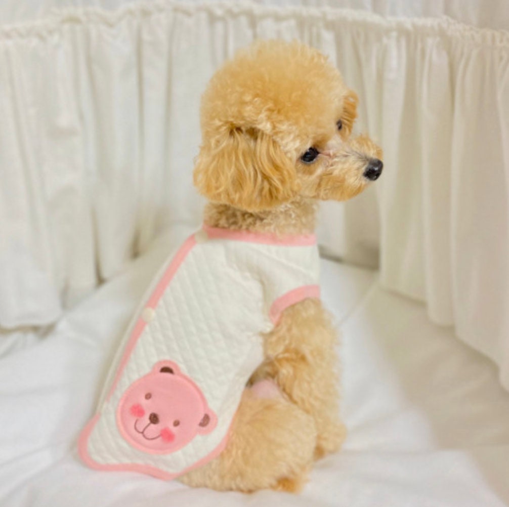 White organic quilted dog vest with pink trim and a pink bear patch