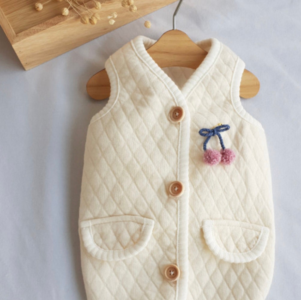 NKpup cream quilted dog vest with brown buttons and a cherry pom-pom embroidery