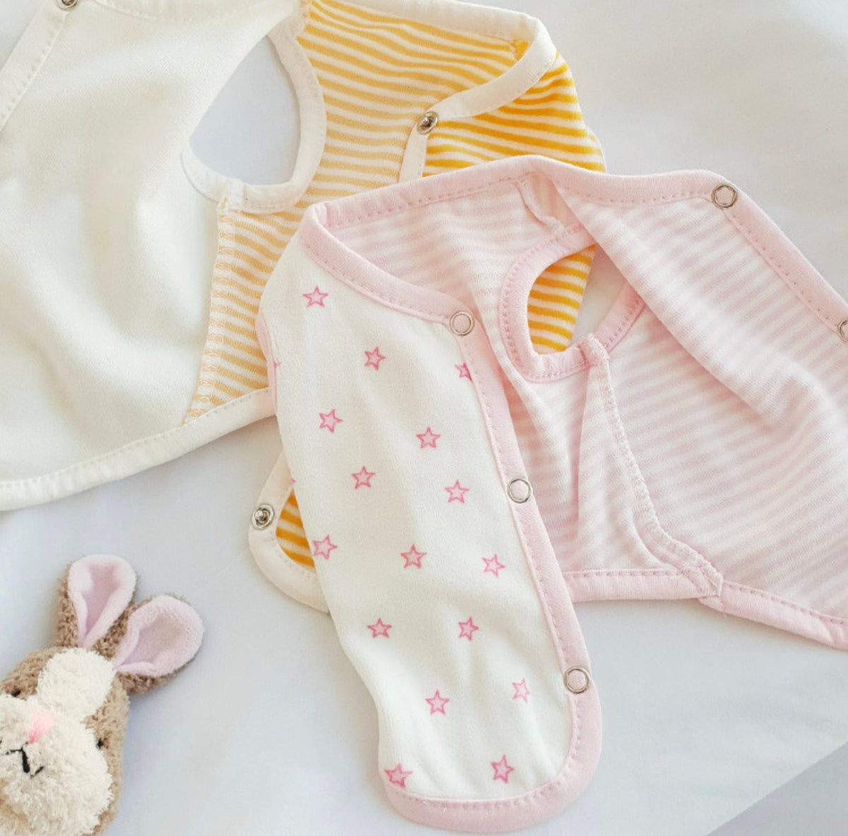 Set of three NKpup Velour Star Dog Vests in white, yellow stripe, and pink stripe with star patterns.