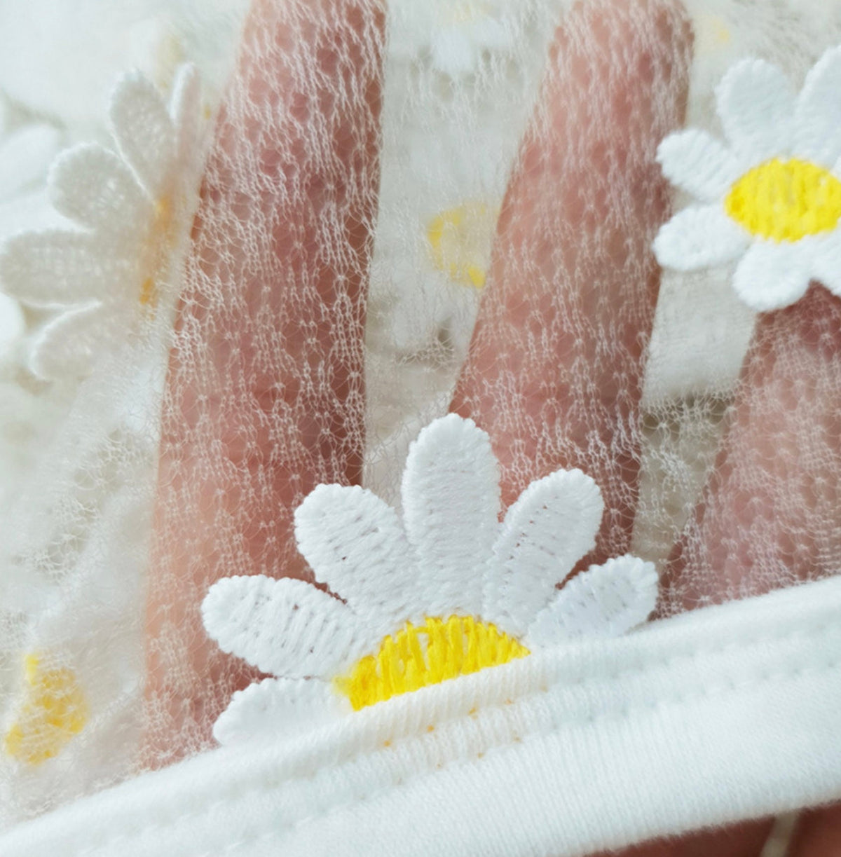 Close-up of the white chiffon fabric and embroidered daisy pattern on an NKpup dog crop top.