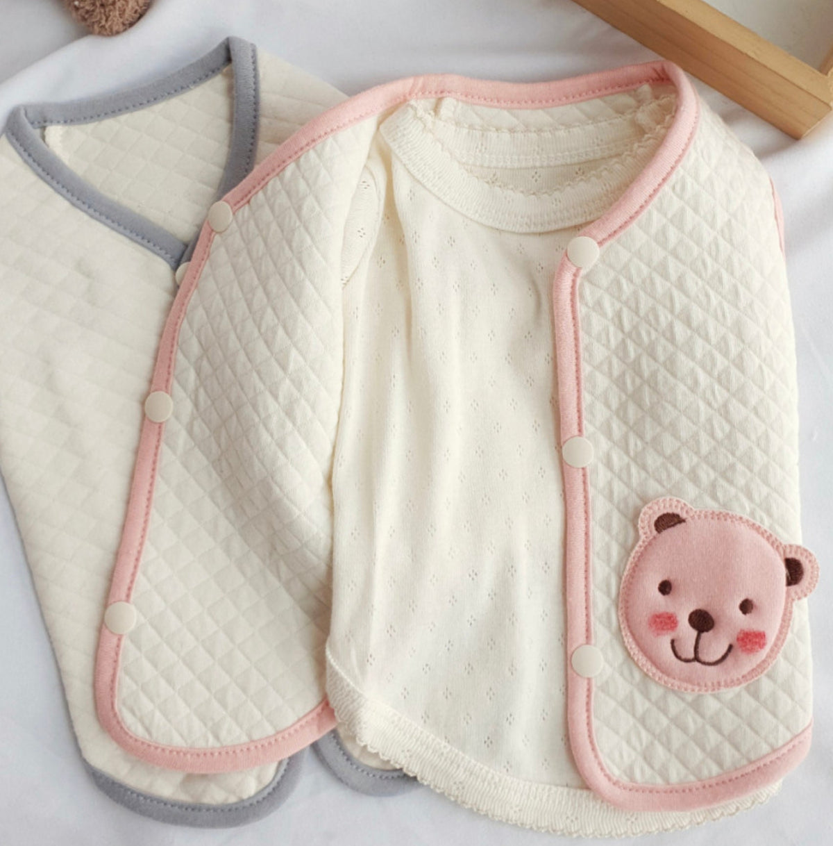 NKpup organic quilted dog vest in cream with pink trim and a cute bear patch.