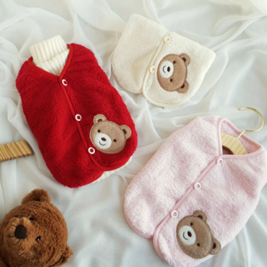 Set of three teddy fleece dog vests in red, cream, and pink featuring bear face patches.