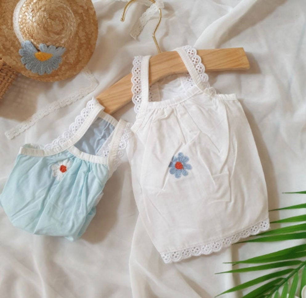 Two embroidered pet tank tops, one white and one light blue, featuring small flower details and lace trim.