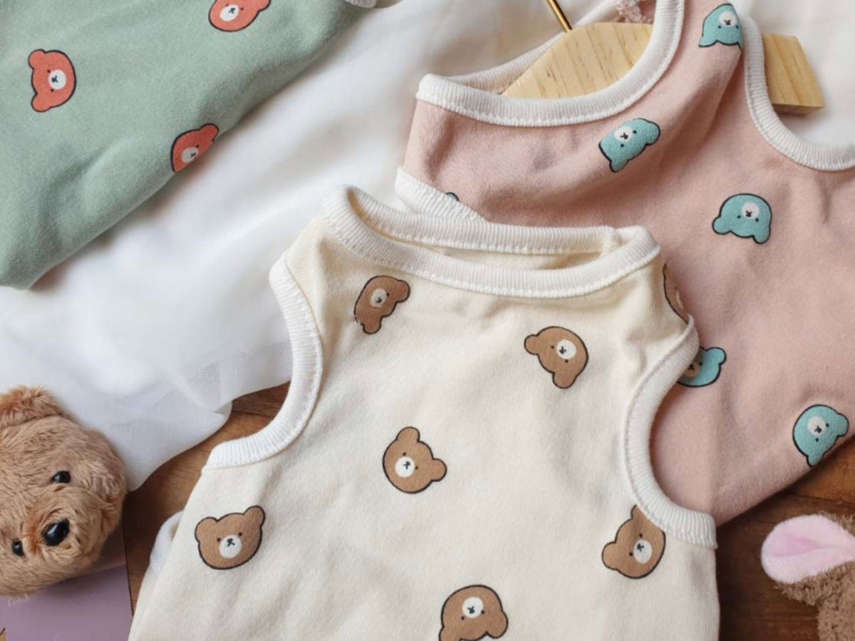 Three bear face patterned dog tank tops in green, pink, and cream colors.