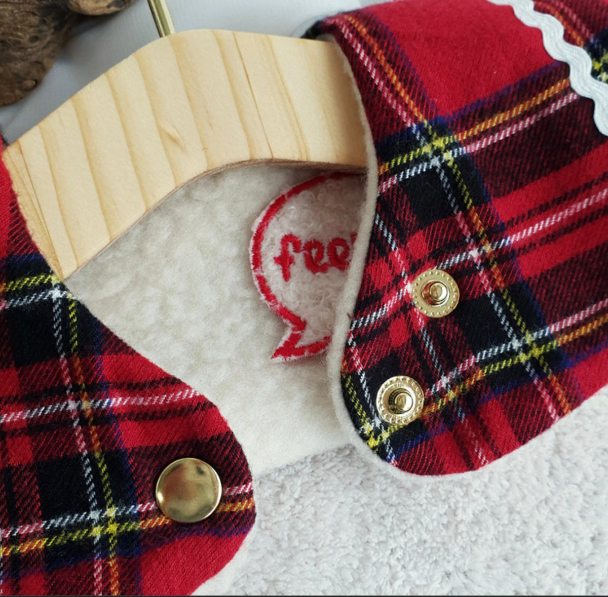 Close-up of NKpup reversible plaid dog cape in red and black with white faux shearling lining.