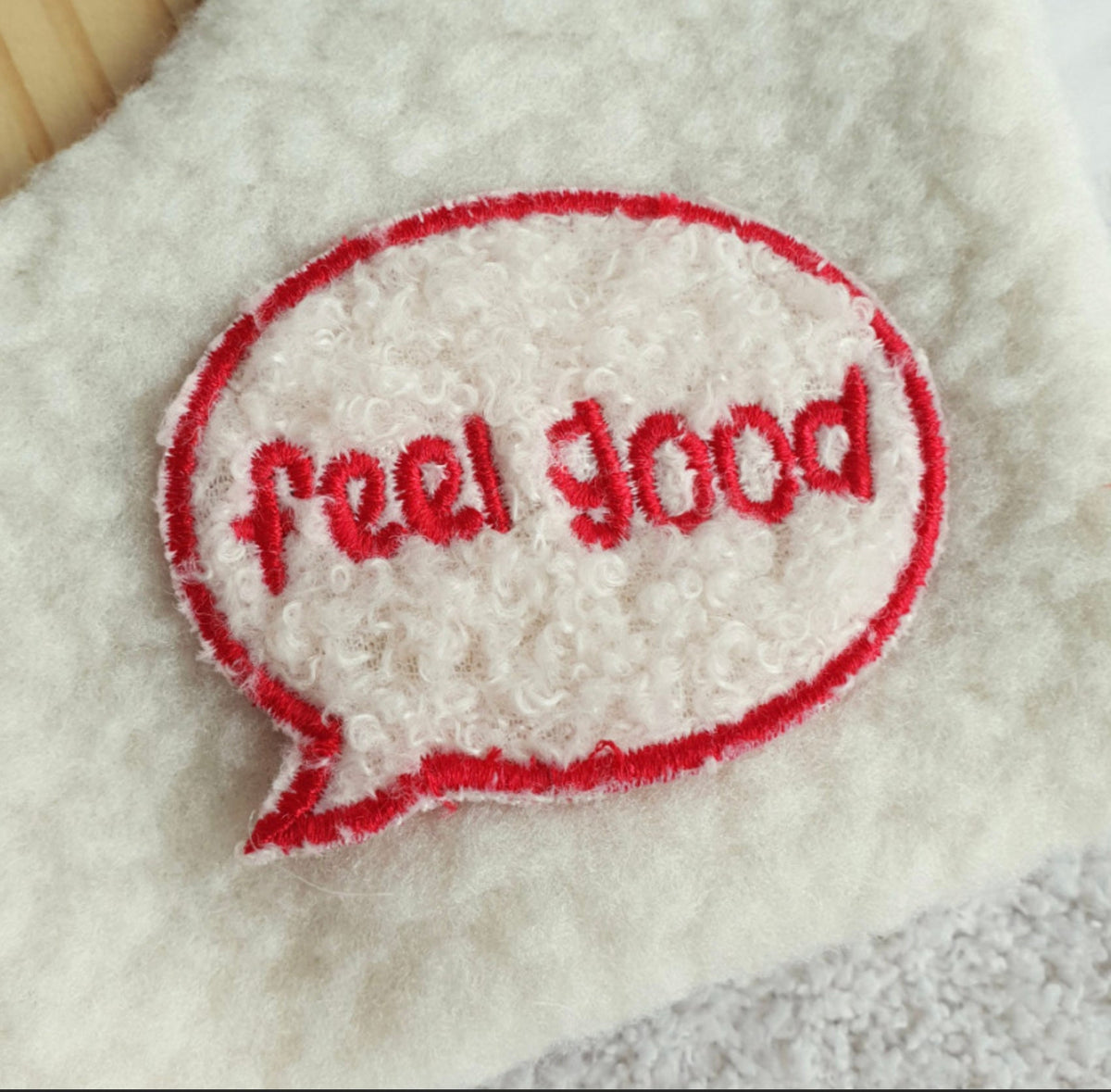 Detail of white fluffy Reversible Plaid Dog Cape by NKpup featuring a red embroidered feel good speech bubble
