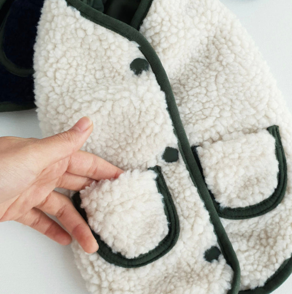 White reversible bomber dog vest with dark green trim and sherpa fleece texture.