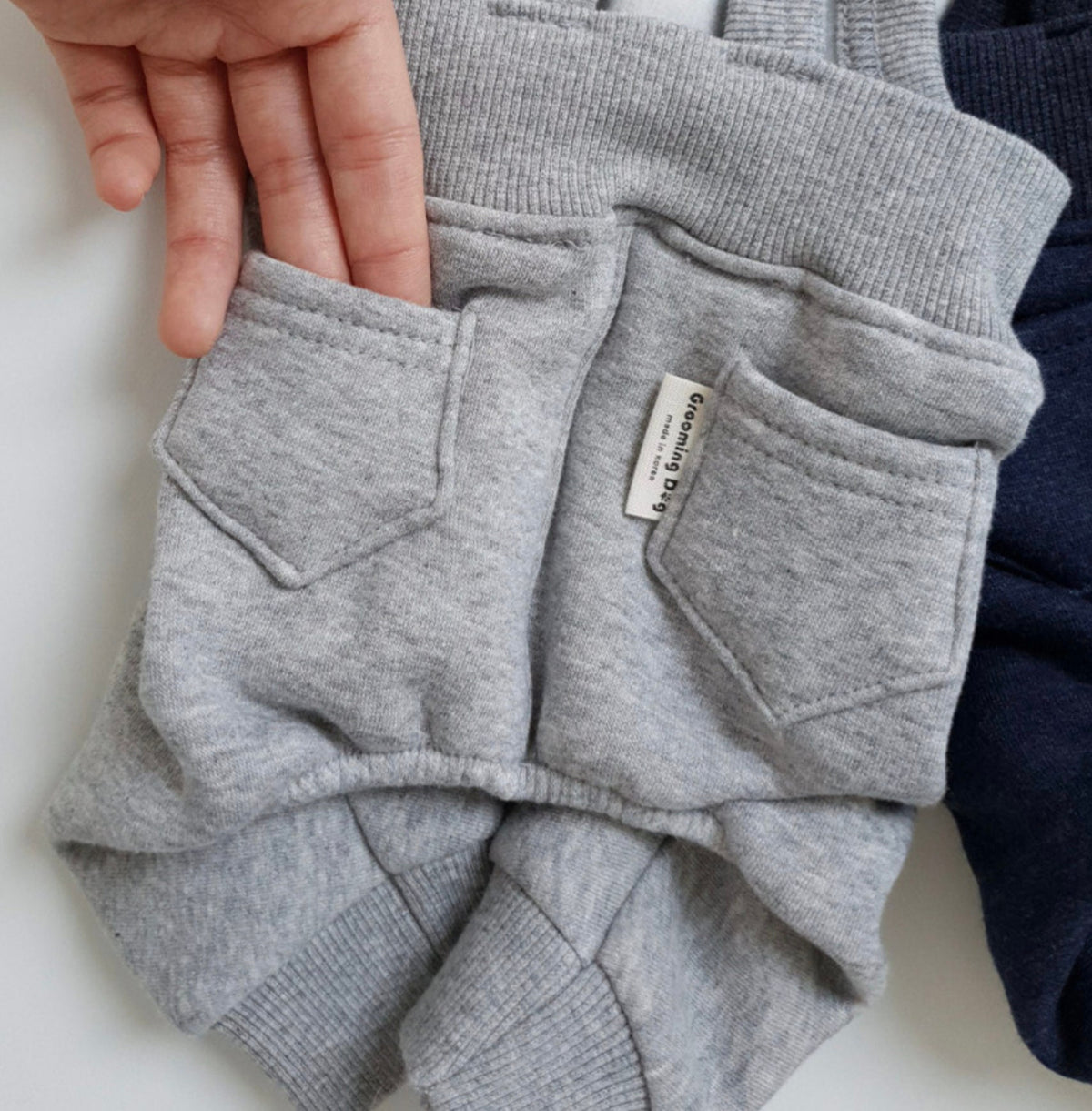 Grey fleece dog suspender overalls with front pockets and ribbed trim.
