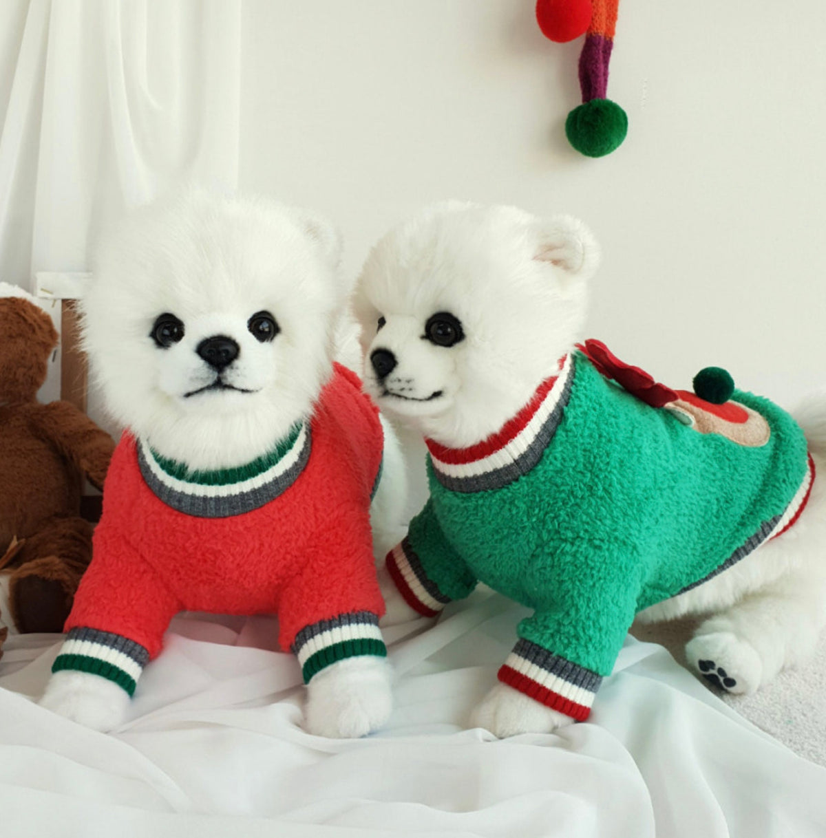 Two small white dogs wearing NKpup Rudolph fleece dog sweatshirts in red and green.