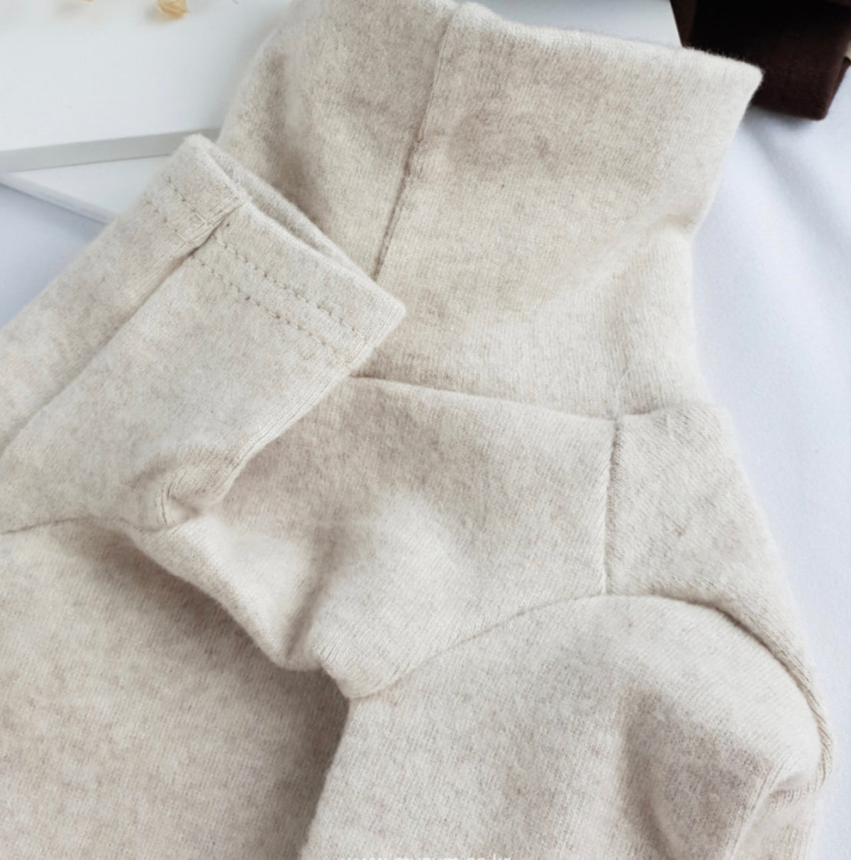 Close-up of a beige NKpup basic dog turtleneck shirt showing the soft fabric and collar detail.