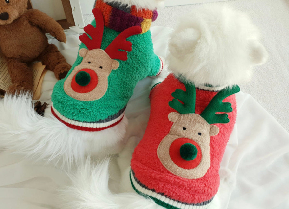 Two dogs wearing Rudolph fleece dog sweatshirts, one in green and one in red with reindeer face details.