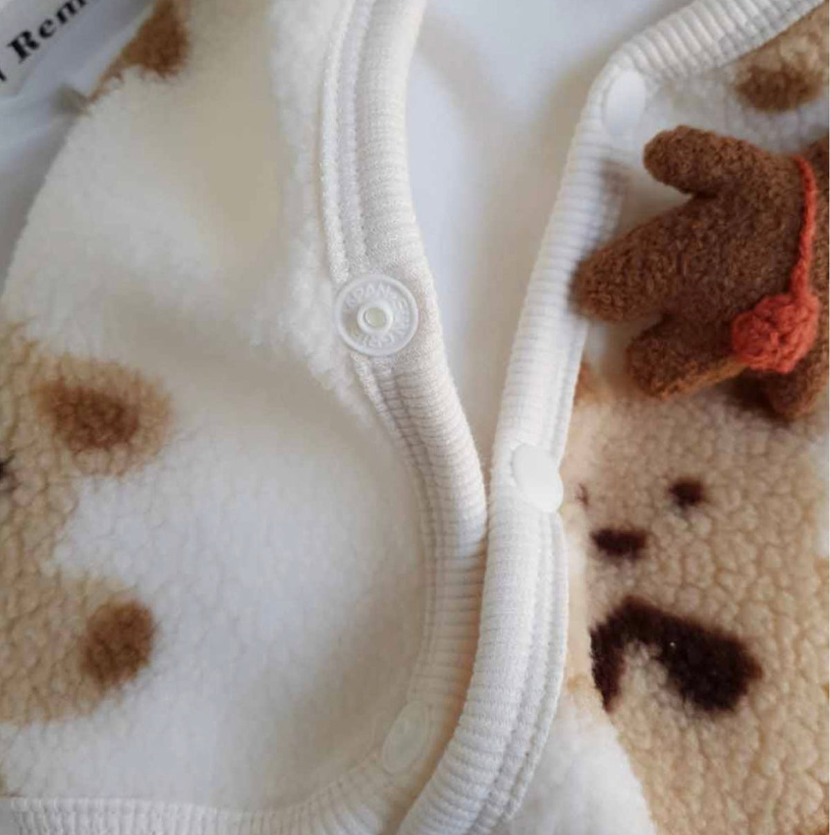 Close-up of NKpup Bear Fleece Dog Vest in cream with brown bear patterns and button closure.