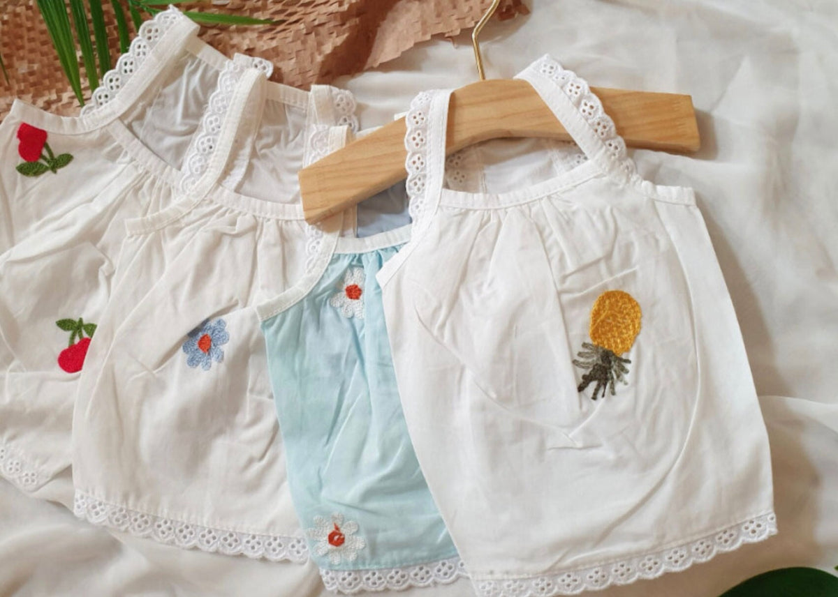 White and light blue embroidered dog tank tops with floral and fruit patterns.